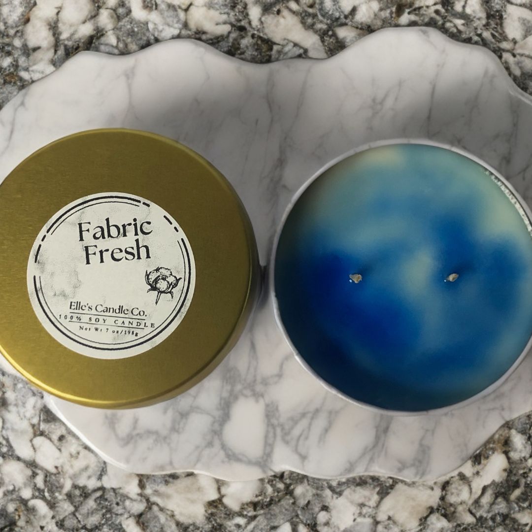Fabric Fresh soy candle in a clear glass jar, scented with clean cotton and linen, photographed on a minimal surface.
